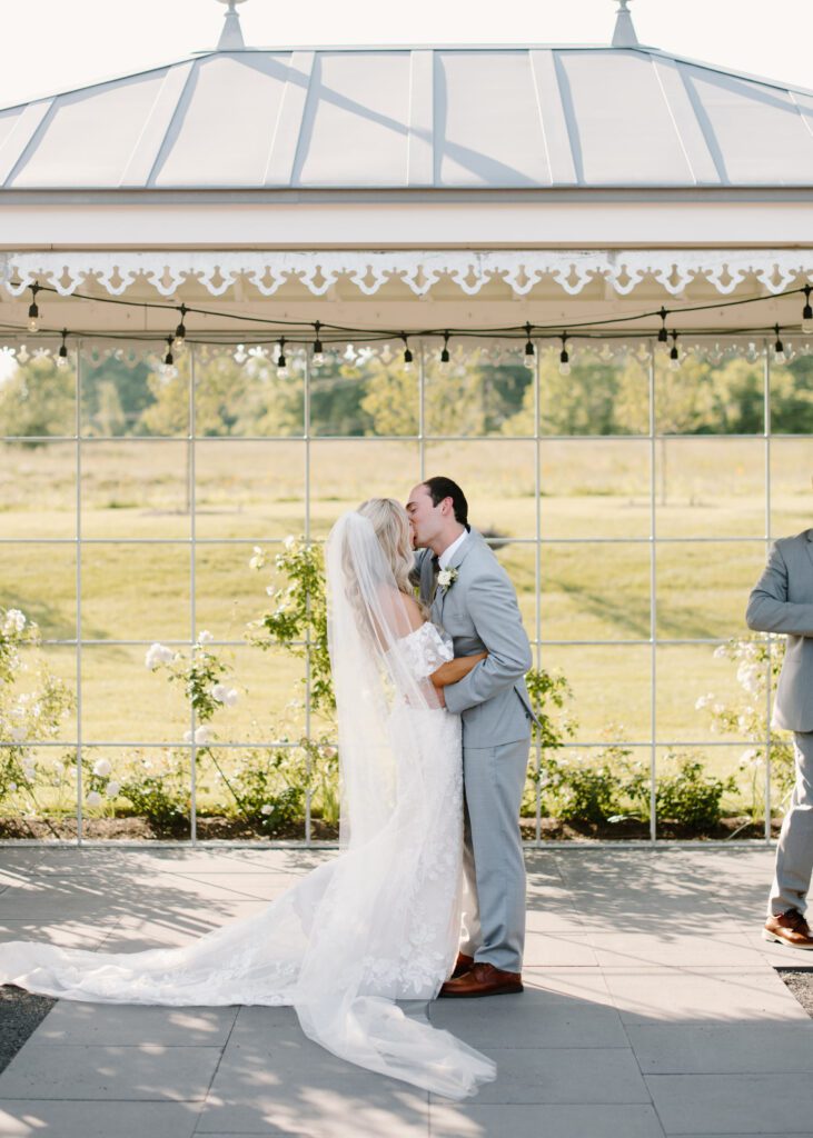 bride and groom kiss during summer wedding ceremony