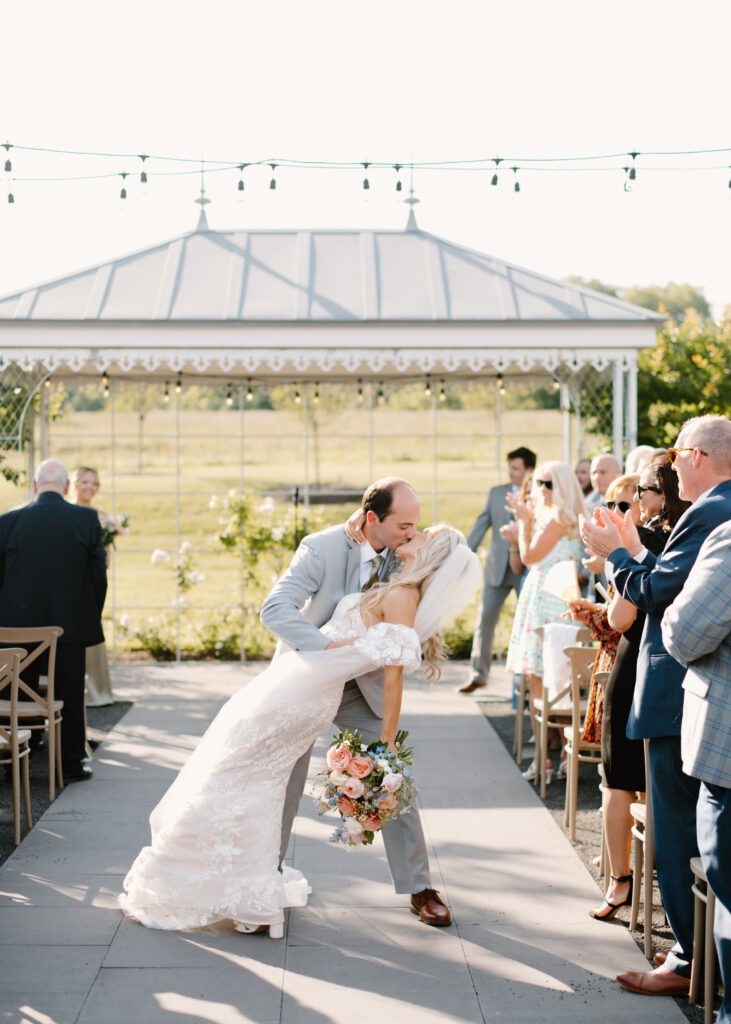bride and groom kiss during summer wedding ceremony